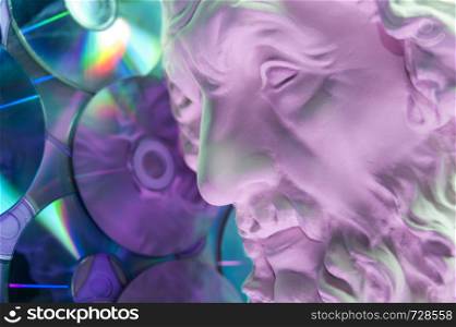 Antique statue of Homer head closeup against the background of glitter CDs. Concept of music, style, vintage. Toned.. Antique statue of Homer head close up on a glitter CDs background. Concept of music, style, vintage.