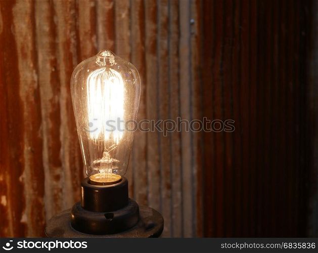 Antique style light light bulb on rusty wall background.