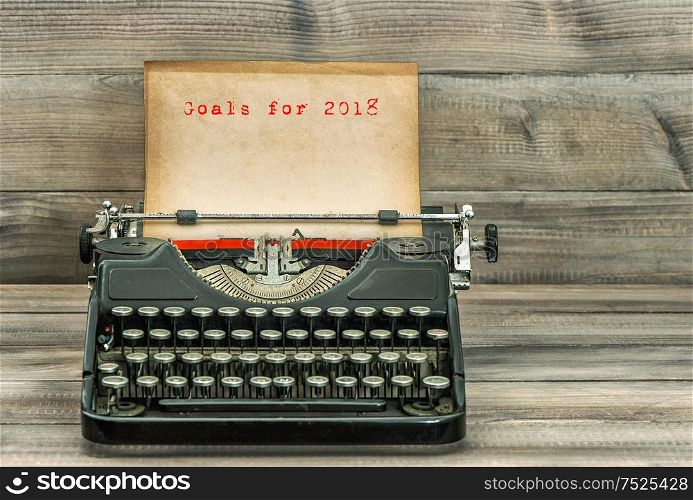 Antique typewriter with grungy paper on wooden background. Goals for 2018. Business concept. Selective focus