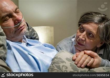 Anxious old woman taking care of sick husband
