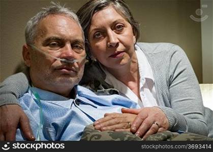 Anxious senior wife holding her sick husband at clinic