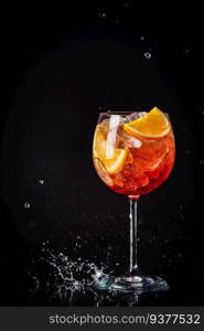 Aperol spritz cocktail in a glass with ice and orange on a black background. Aperol spritz cocktail