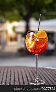 Aperol spritz cocktail in a glass with ice and orange on an outside street background. Aperol spritz cocktail