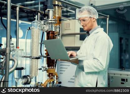 Apothecary scientist working with laptop near CBD oil extractor and a scientific machine used to create medicinal cannabis products.. Apothecary scientist working with laptop near CBD oil extractor in laboratory.