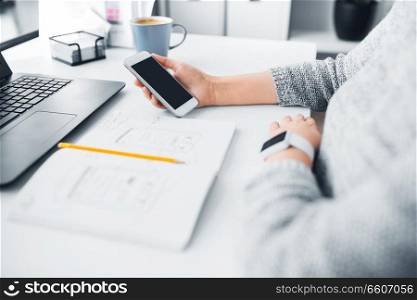 app design, technology and business concept - web designer or developer with smartphone and sketch in notebook working on user interface at office. web designer creating mobile user interface