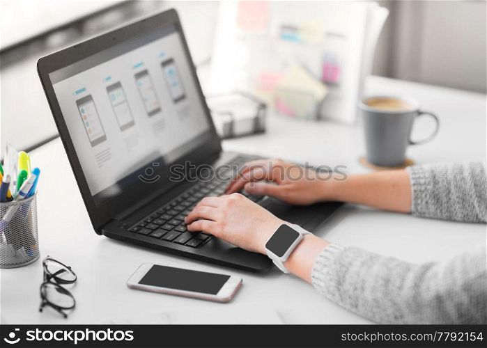 app design, technology and business concept - web designer or developer with smart watch working on user interface and drawing sketches at office. web designer with laptop working on user interface