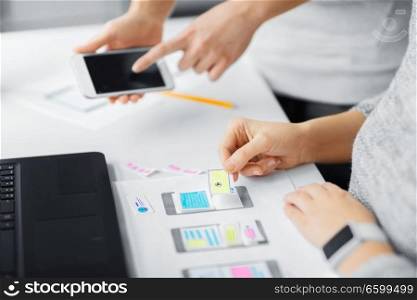 app design, technology and business concept - web designers or developers with smartphone working on user interface at office. web designers creating mobile user interface