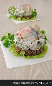 Appetizer of chopped herring, radish and apple and sour cream on a slice of rye bread
