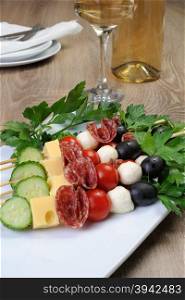 Appetizer of salami with mozzarella, olives, cherry tomatoes, cucumber and cheese on a skewer