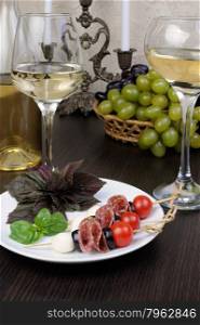 Appetizer of salami with mozzarella, olives, cherry tomatoes on skewers with basil