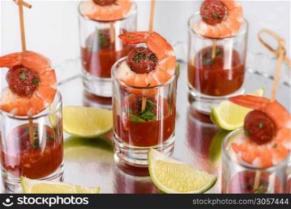 Appetizer of shish kebab with shrimps and chorizo sausages with barbecue sauce in a glass