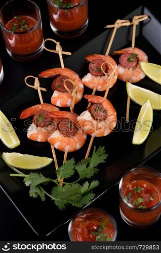 Appetizer of shish kebab with shrimps and chorizo sausages with barbecue sauce in a glass