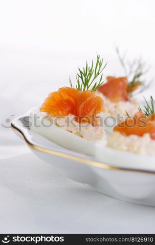 Appetizer of stuffed eggs stuffed with salmon pate and yolks with salmon slices. Holiday table idea  