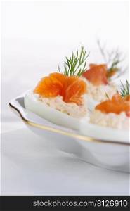 Appetizer of stuffed eggs stuffed with salmon pate and yolks with salmon slices. Holiday table idea  