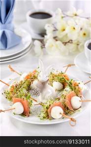 Appetizer quail egg stuffed with alfalfa sprouts with a slice of salmon, on a wooden skewer. Buffet serving for the Easter table.