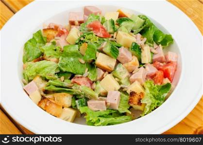 Appetizer salad with cheese, ham, fresh tomatoes, lettuce, sunflower seeds and crackers