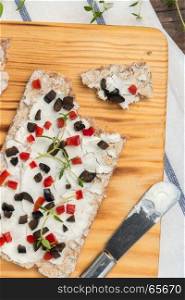 Appetizer toast with cheese, red bell pepper, olives and thyme. Healthy food, vegan or diet nutrition concept on wooden table
