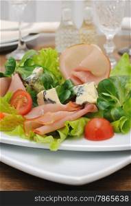 Appetizer with ham and blue cheese in lettuce leaves with corn salad