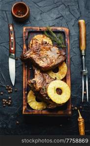 Appetizing beef meat baked with pineapple rings. Beef entrecote in fruit marinade on cutting board. Meat grilled with pineapple rings.