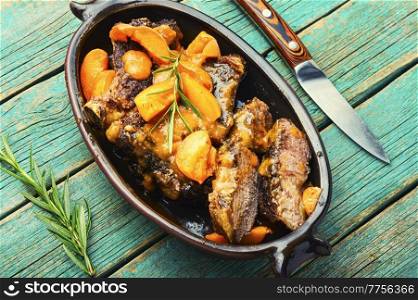 Appetizing beef meat roasted in apricots on the plate. Fried meat ribs in fruit marinade.