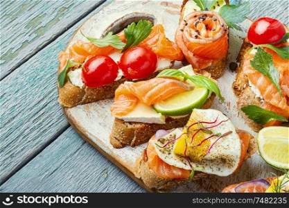 Appetizing bruschetta.Traditional italian bruschetta.Open sandwich with salmon and vegetables. Toasts with salted salmon