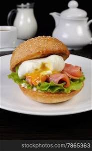 Appetizing bun with sesame seeds and thin slices of salmon and poached egg