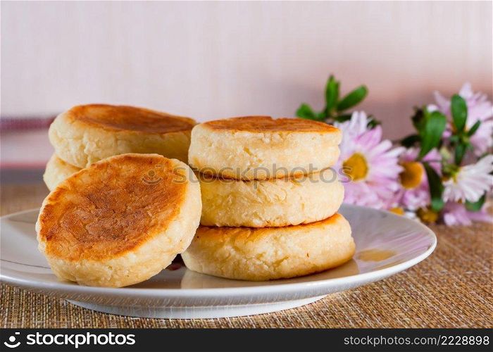 Appetizing cheesecakes on a plate on a brown background. Dish of cottage cheese for breakfast.. Cheesecakes on a plate on a brown background. Dish of cottage cheese for breakfast.