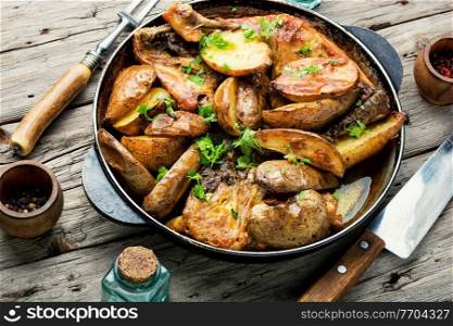 Appetizing chicken meat with potatoes roasted in a pan.Chicken pieces baked with vegetables. Chicken baked with potatoes in a iron cast pan
