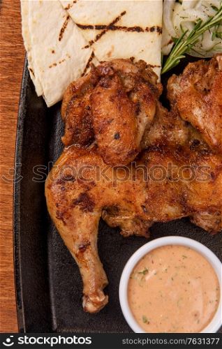 Appetizing grilled juicy chicken with golden brown crust served with barbeque sauce, rosemary and pita bread.. Appetizing grilled juicy chicken