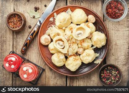 Appetizing homemade dumplings with mushroom filling on old wooden table. Homemade varenyky with mushrooms.