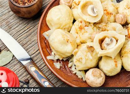 Appetizing homemade dumplings with mushroom filling on old wooden table. Homemade varenyky with mushrooms.