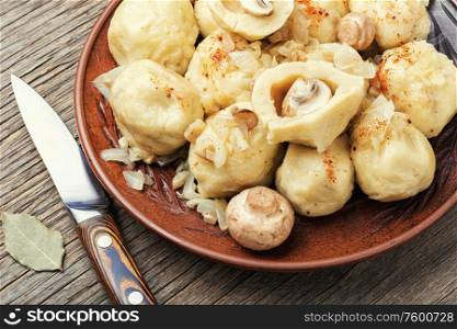 Appetizing homemade dumplings with mushroom filling on old wooden table. Plate with tasty dumplings