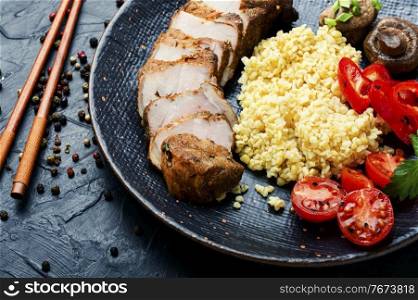 Appetizing meat steak with bulgur porridge and vegetables. Sliced meat and bulgur porridge