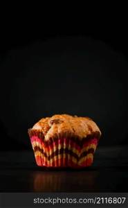 Appetizing muffin on a black background. Sweet homemade raisin cake. Vertical photo. Muffin on a black background. Sweet homemade raisin cake. Vertical photo