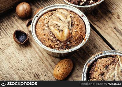 Appetizing muffins with banana, nuts on wooden background. Muffins with banana.