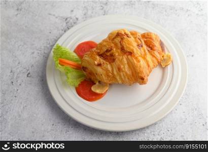 Appetizing of croissant with hotdog on white dish and decoration with tomato sliced, carrot and lettuce beautifully, copy space
