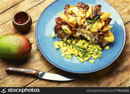 Appetizing pork meat baked with mango and cheese. Baked meat with mango