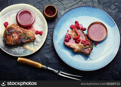 Appetizing pork steak on a plate and raspberry sauce. Pork steak with berry sauce.