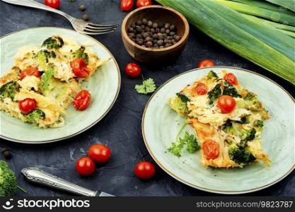 Appetizing potato casserole with broccoli and tomatoes on a plate.. Potato gratin or graten