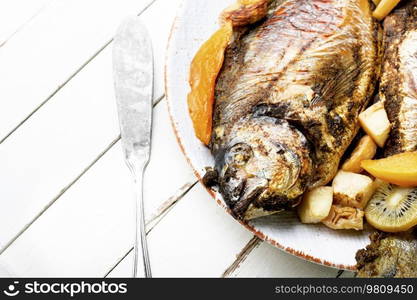 Appetizing river carp baked with fruits. Grilled fish. Baked carp with fruit.