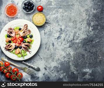 Appetizing salad with calamari, salmon and vegetables.. Salad with squid and seafood