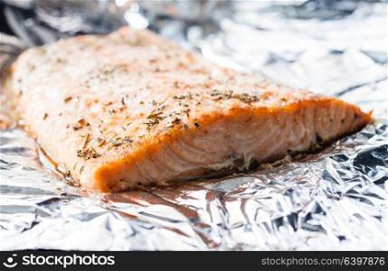 Appetizing salmon steak baked with herbs in aluminum foil. Baked salmon on the foil