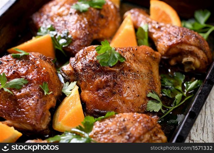appetizing slices of baked chicken with crispy fried crust and oranges in a baking sheet