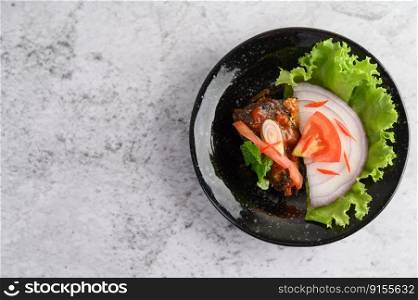 Appetizing Spicy Canned Sardine salad in spicy sauce in black ceramic bowl