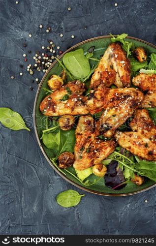 Appetizing spicy chicken wings with vegetables. Top view. Delicious grilled chicken wings.