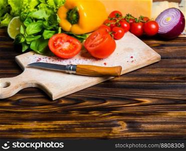 Appetizing still life. Fresh bulgarian yellow pepper, cherry tomatoes, lettuce leaves, red onion, green basil on wooden board. The knife for cutting vegetables.. Appetizing still life. Fresh bulgarian yellow pepper, cherry tomatoes, cheese, lettuce leaves, red onion, green basil on wooden board. The knife for cutting vegetables. Top view