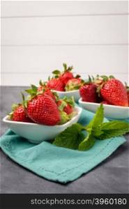 Appetizing strawberry in the bowl on a black slate table top.