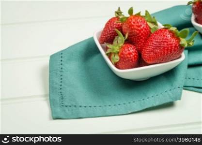 Appetizing strawberry in the bowl on a wooden background.