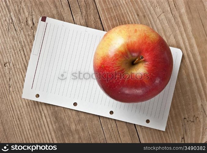 apple and a note on a wooden background