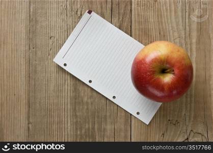 apple and a note on a wooden background